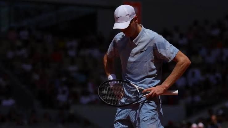 Jannik Sinner playing a backhand shot during a professional tennis match.