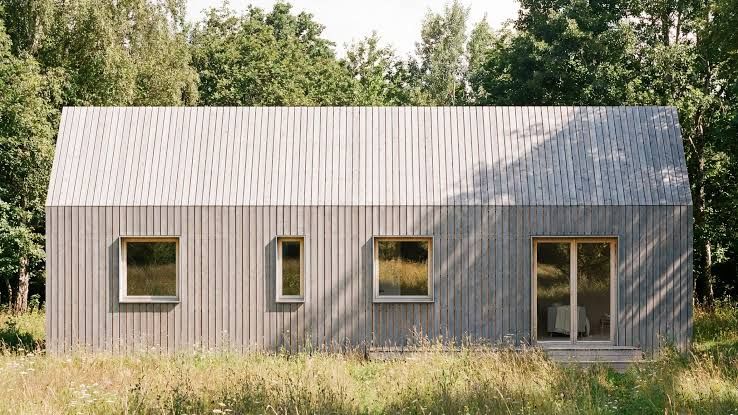 Architectural render of Plana House, a small two-bedroom timber home with a pitched roof in a wooded area.