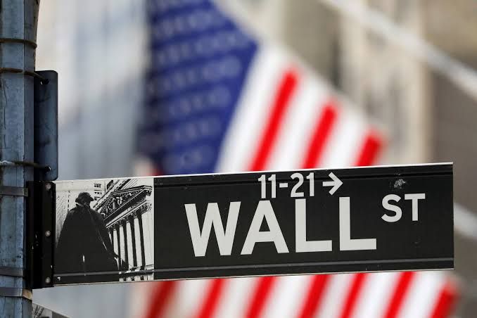 Wall Street sign outside the New York Stock Exchange building in Manhattan on a clear day.