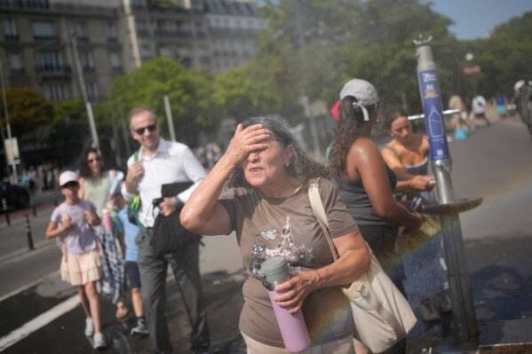 Tourists cooling off at a public water fountain in Paris during a heat wave on June 26, 2026.
