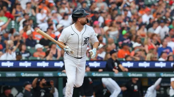 Jake Rogers wearing a Tigers jersey, standing behind home plate in a catcher's gear during an MLB game.