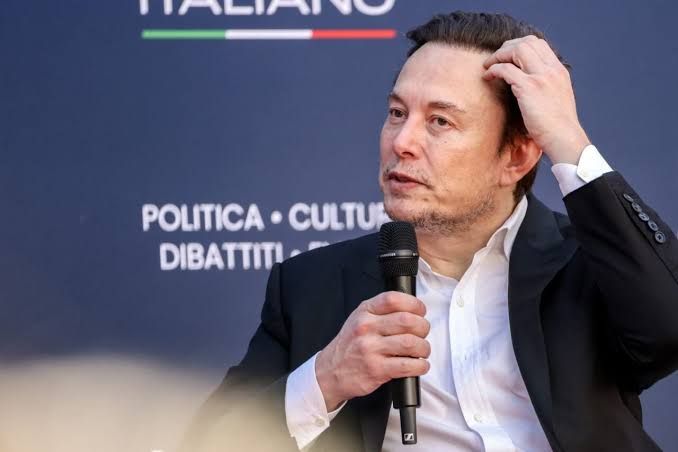 Elon Musk looking at a display during a professional event, representing his leadership in current tech acquisitions.