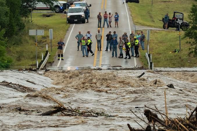 People watch as the Pedernales River overflows onto Ranch Road 1623 in Stonewall during severe flooding.