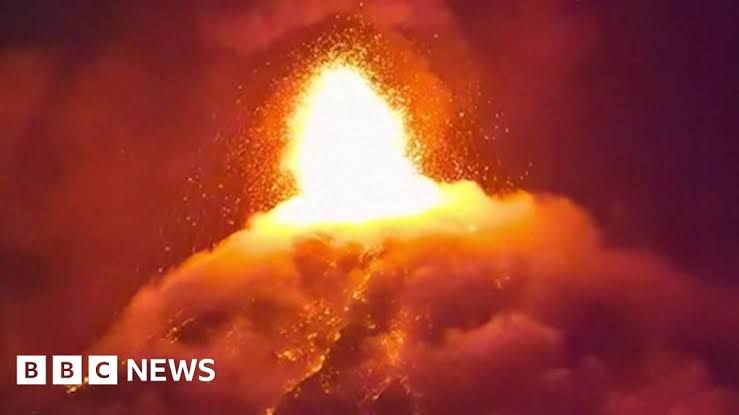 Orange lava and gray ash plumes erupting from the summit of the Fuego volcano in Guatemala.