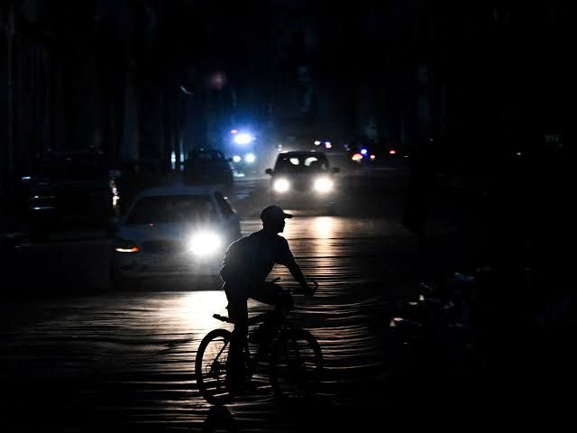 A dark city street in Havana, Cuba, during a nighttime blackout with minimal ambient light.