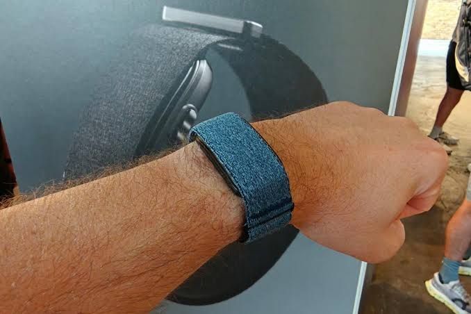 Garmin Cirqa fitness tracker worn on a wrist next to running shoes.