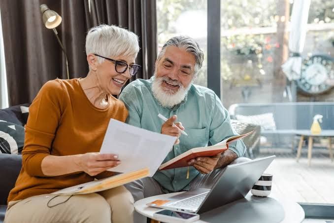 An older couple sitting at a table and reviewing financial documents together.
