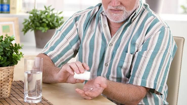 An elderly person holding a small pill bottle, reflecting on the choice of long-term preventive medication.