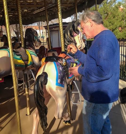Artist Ron Larson carefully painting the saddle of a fiberglass carousel horse in St. George.