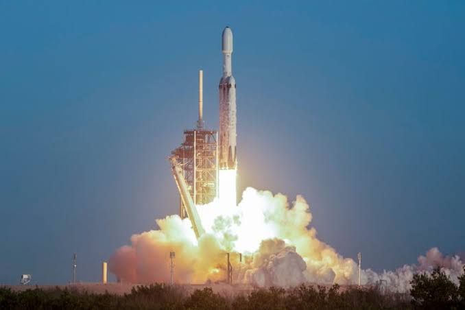 SpaceX Falcon Heavy rocket lifting off from a launch pad to carry the Nancy Grace Roman telescope into deep space.