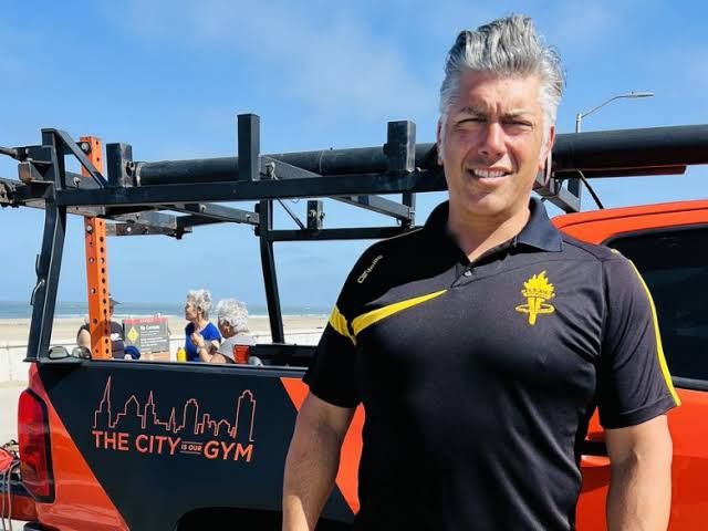 Greg Bianchi stands next to his modified orange gym truck, which features a pull-up bar and weight rack, in San Francisco.
