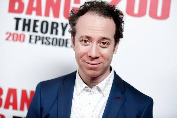 Kevin Sussman wearing a casual blazer while posing for a professional headshot during a media event.