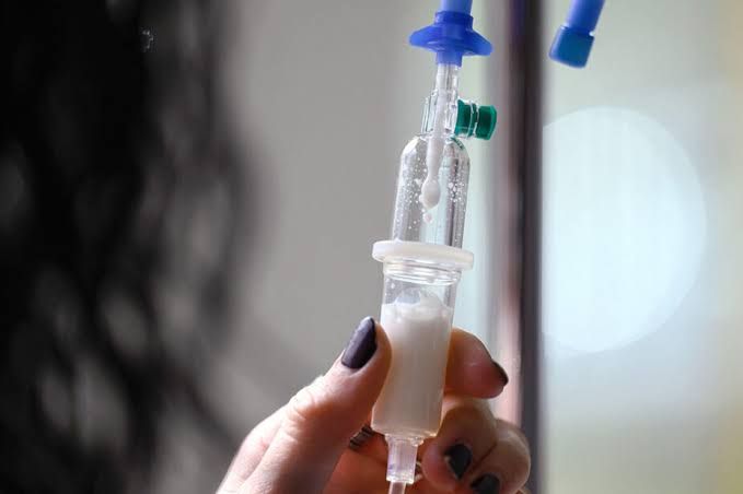 A clinical professional prepares an intravenous medication infusion in a hospital setting for an elective procedure.