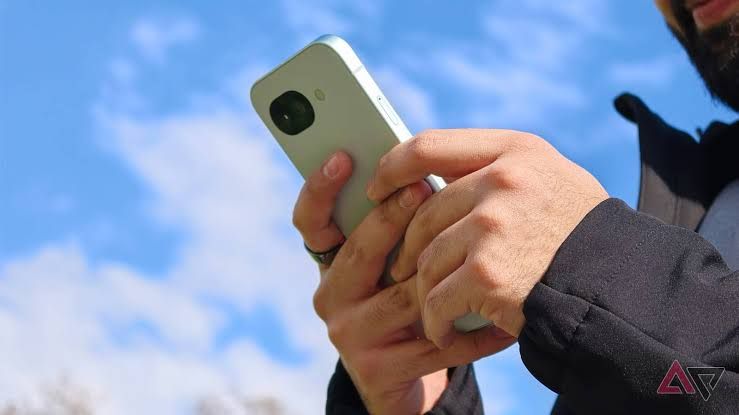 A person holding the Google Pixel 10a smartphone, showcasing the device's hardware design and screen.