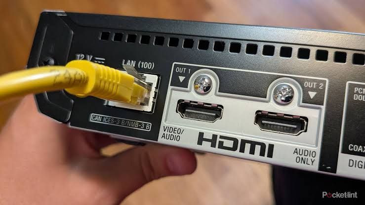Close up of an Ethernet cable held above a vintage gaming console to illustrate wired connectivity.