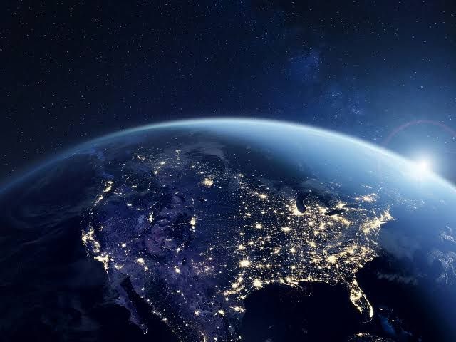 Earth at night with city lights visible from space to represent global communication infrastructure.