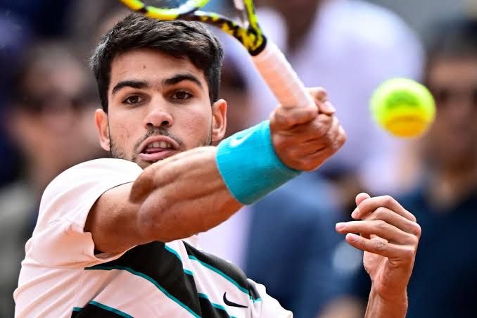 Carlos Alcaraz adjusting his wrist band during a professional tennis match.