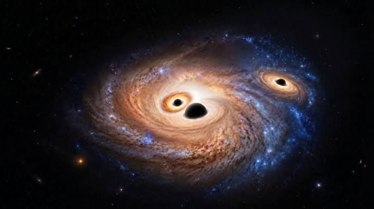 Visualization of three black holes inside a distant galaxy with glowing accretion disks and gas clouds.