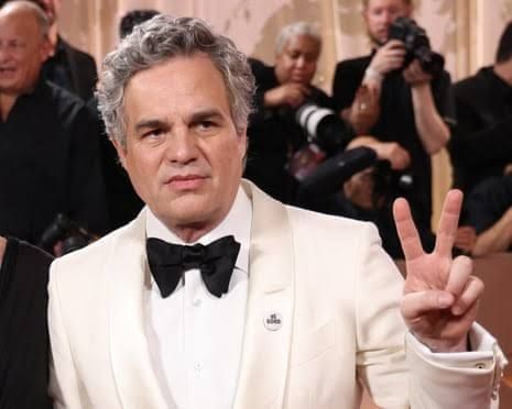 Mark Ruffalo gestures with a peace sign while wearing a tuxedo at the Golden Globe Awards.