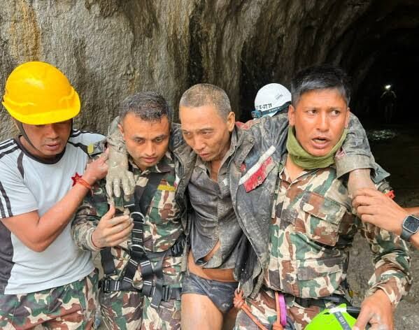 A rescue worker and a survivor in a remote tunnel after the Nepal flooding disaster.