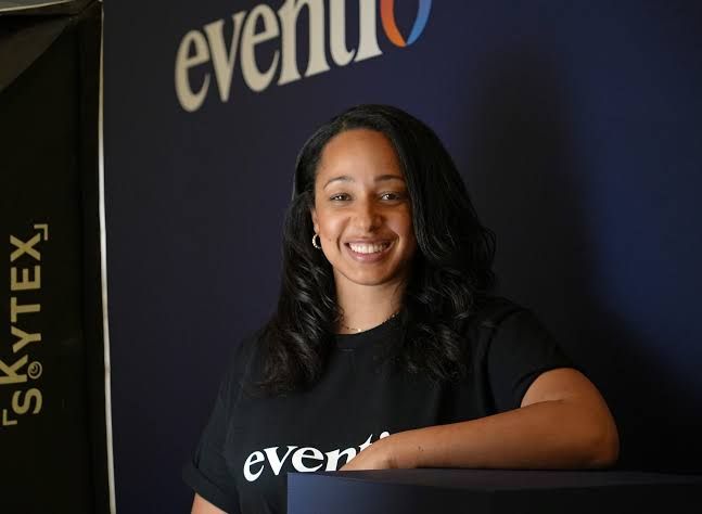 Erin Kerner, co-founder of Eventio, stands before the company's new website interface during a local Erie business event.