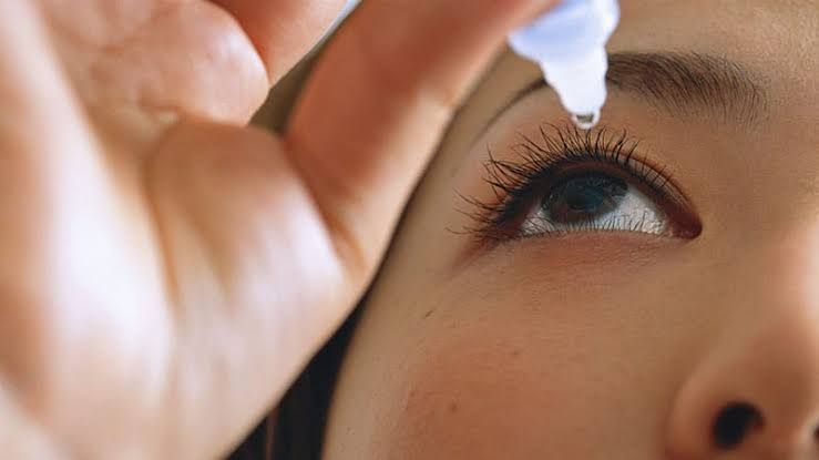 A close-up view of a patient's eye during an ophthalmological exam in a dimmed clinical testing environment.