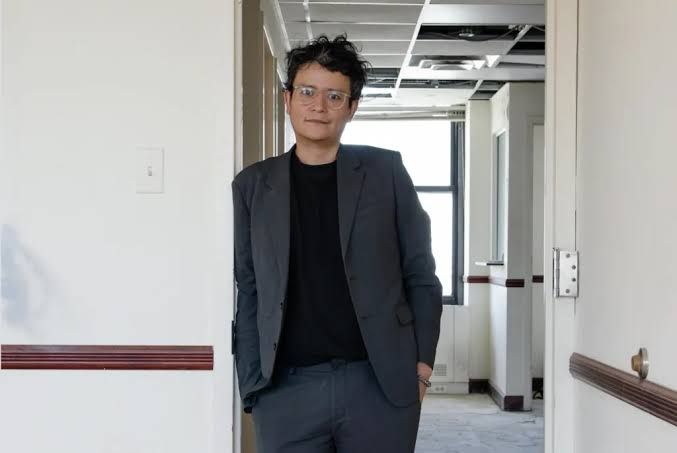Francisco Correa Cordero wearing a dark blue suit and glasses leans against a white doorway.