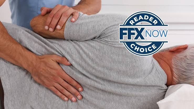 A therapist performs back treatment on a patient while a Reader Choice badge is overlaid on the image.