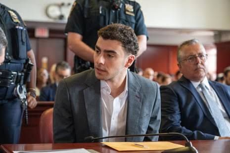 Luigi Mangione sits in a courtroom alongside his legal defense team during a pre-trial hearing in New York.