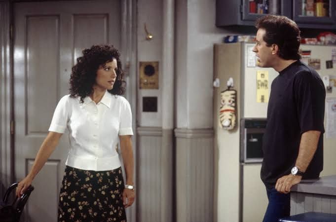 Julia Louis-Dreyfus in character as Elaine Benes alongside Jerry Seinfeld on the set of their 90s sitcom.