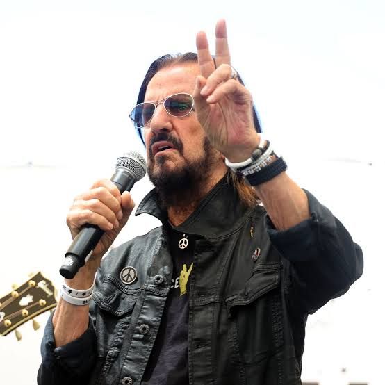 Ringo Starr seated at his drum kit during a live concert performance.