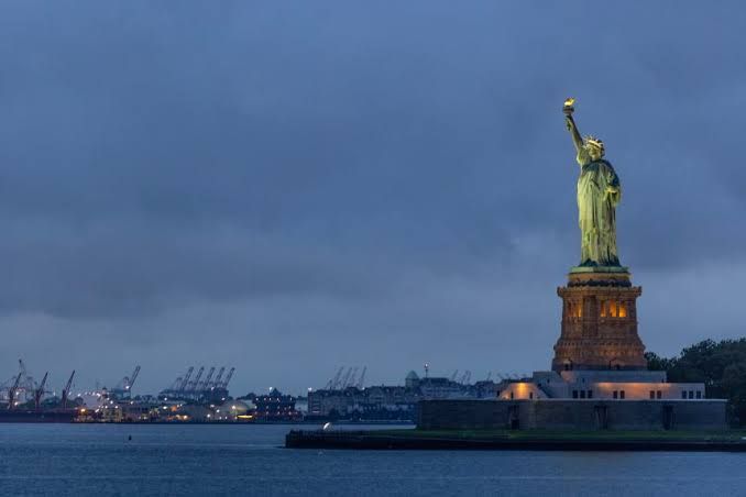 The Statue of Liberty viewed from the water with a cloudy sky in the background.