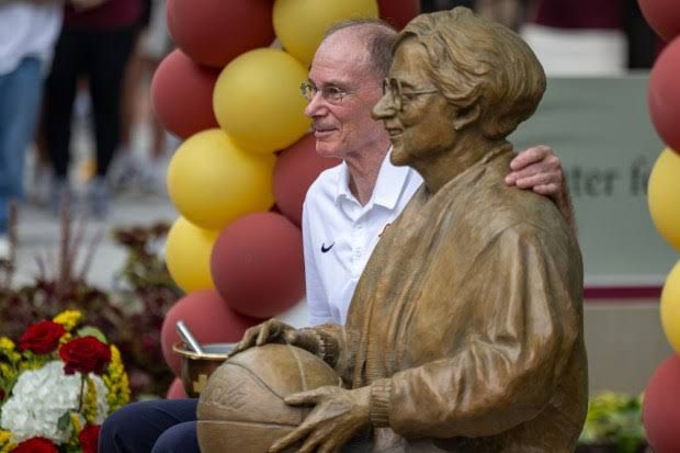 A bronze statue of the late Sister Jean sitting on a bench while holding a basketball at Loyola University Chicago.