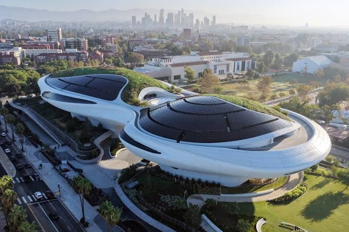 Aerial view of the Lucas Museum of Narrative Art in Los Angeles featuring a curvy, modern white structure and green roofs.