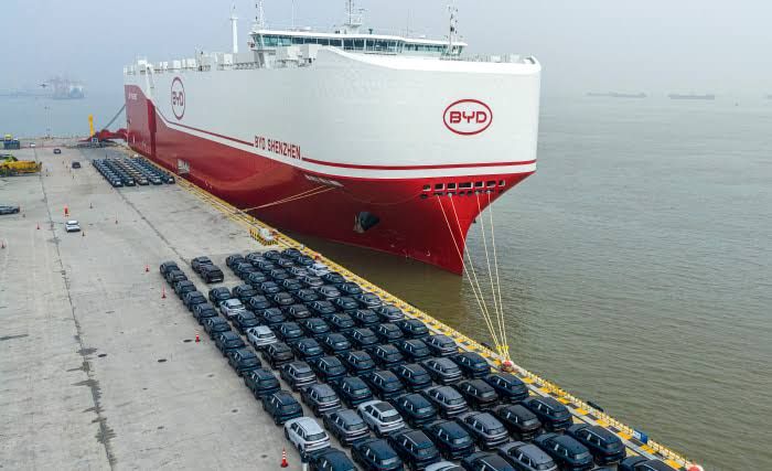 Shipping containers stacked high at a busy Chinese port during cargo loading operations.