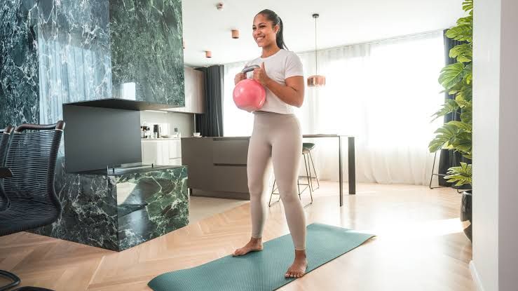 A trainer demonstrating a kettlebell snatch movement with proper form to build core stability.