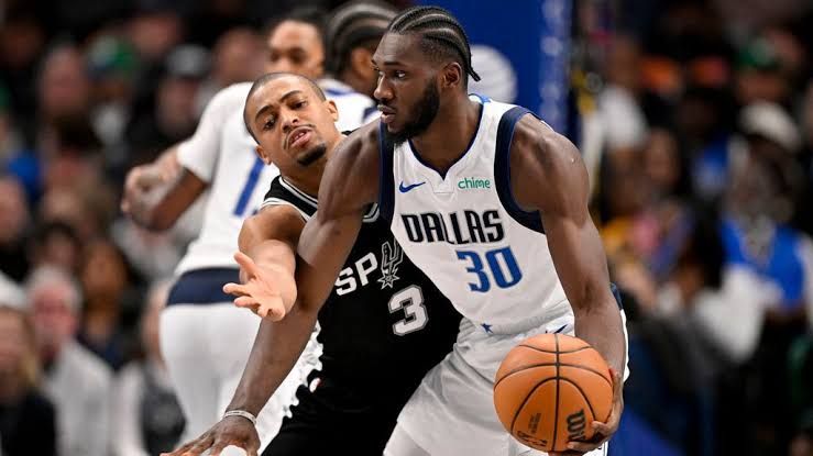 Moussa Cisse stands on the basketball court during a game wearing a Dallas Mavericks uniform.