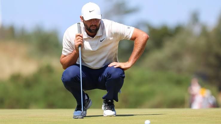 Scottie Scheffler preparing to hit a golf ball on the course during a tournament.