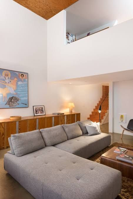 A minimalist living space featuring high ceilings, open design, and industrial windows designed by Frank Gehry.