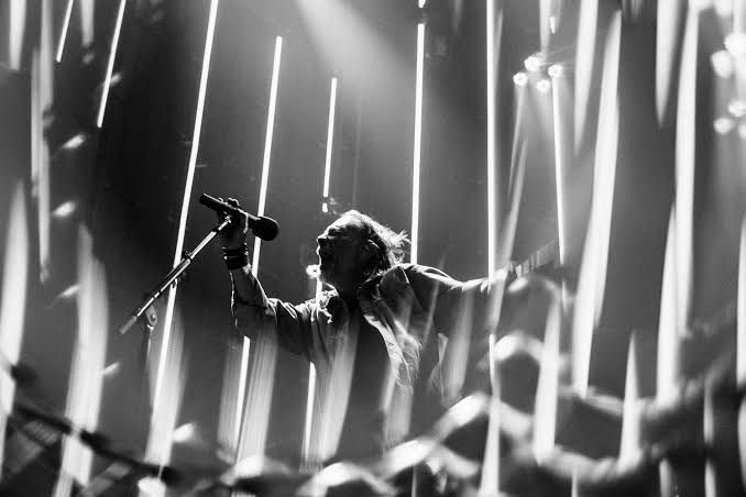 Radiohead performing live on stage at a large arena in Europe during their 2025 tour.