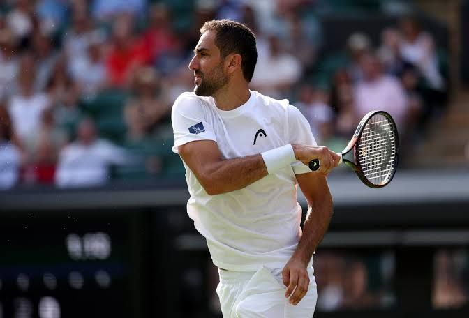 Marin Cilic wearing a white polo shirt and holding a tennis racket during the 2026 Wimbledon Championships.
