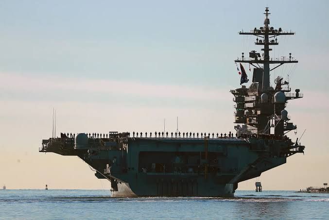 The USS Abraham Lincoln aircraft carrier deck lined with crew members during a 2021 deployment.