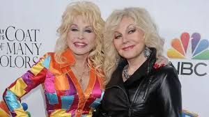Dolly Parton and her sister Stella Parton smiling together at a red carpet event in 2015.