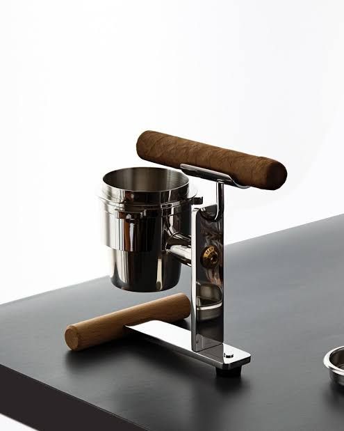 The Achille cigar ashtray by John Meng sits on a table, showcasing a stainless steel portafilter bowl and Beech wood.
