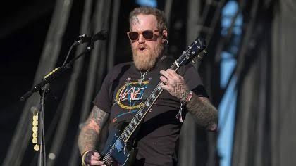 Brent Hinds performing on stage with his guitar during a live show.