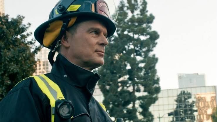 Peter Krause as Captain Bobby Nash looking concerned while standing outside a building in 9-1-1.