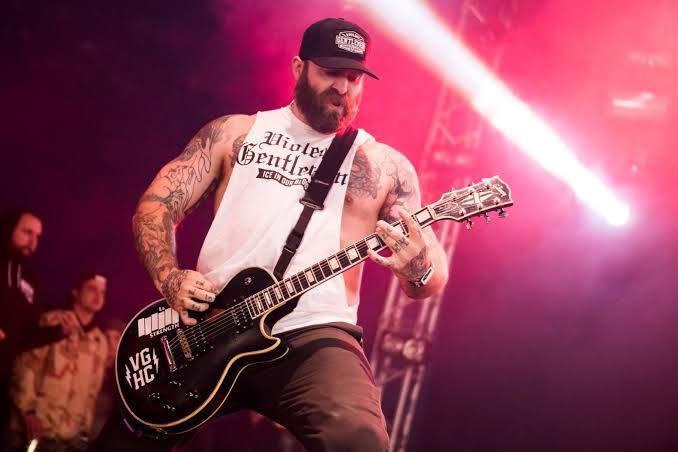Andy Williams performing on stage with a guitar, representing his long tenure as a metalcore musician.