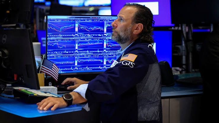 Traders at the New York Stock Exchange monitoring stock market performance and interest rate data on electronic displays.