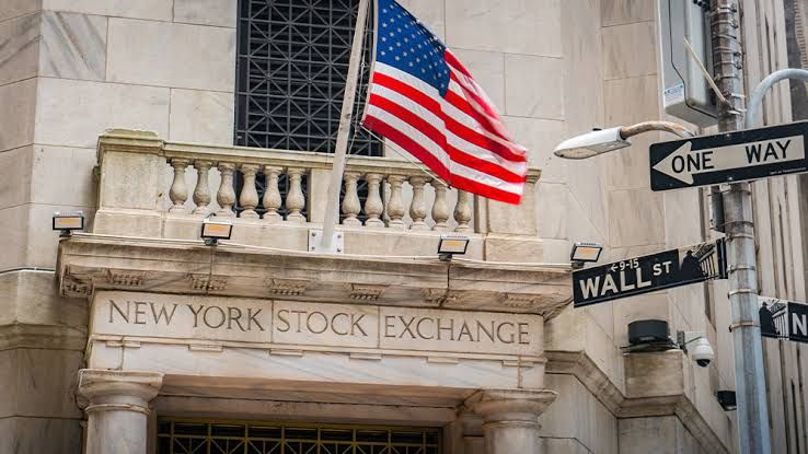 A digital stock market ticker display showing rising green arrows and company symbols for Nasdaq and S&P 500.