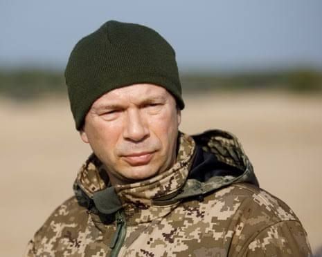 Oleksandr Syrskyi wearing a green beanie and camouflage jacket during a field observation.